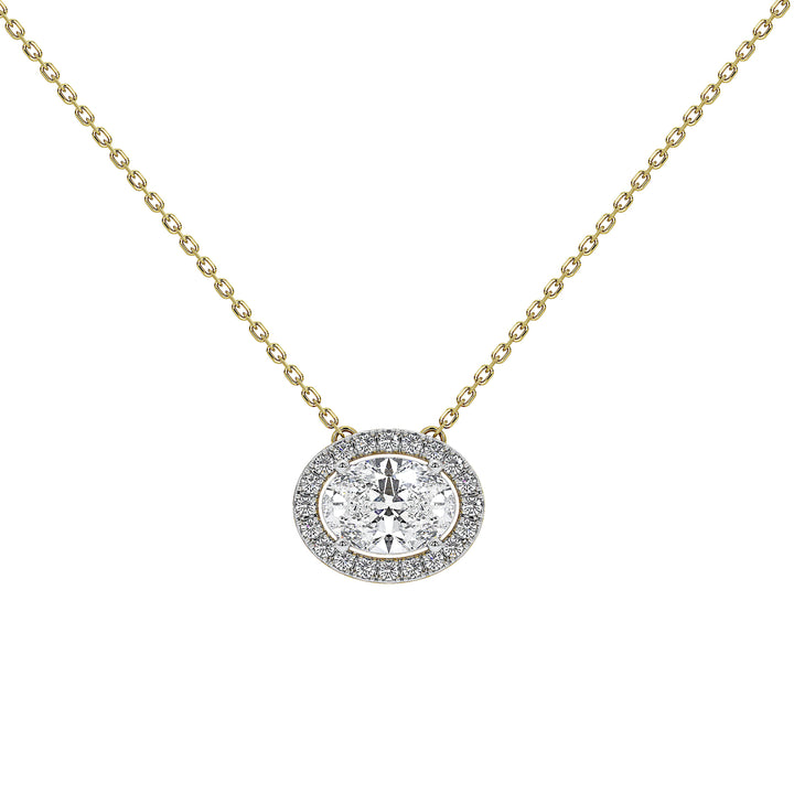A delicate yellow gold chain necklace with an oval halo pendant. The pendant features a central round-cut clear diamond surrounded by a halo of smaller clear stones in a silver-toned setting, all on a plain white background.